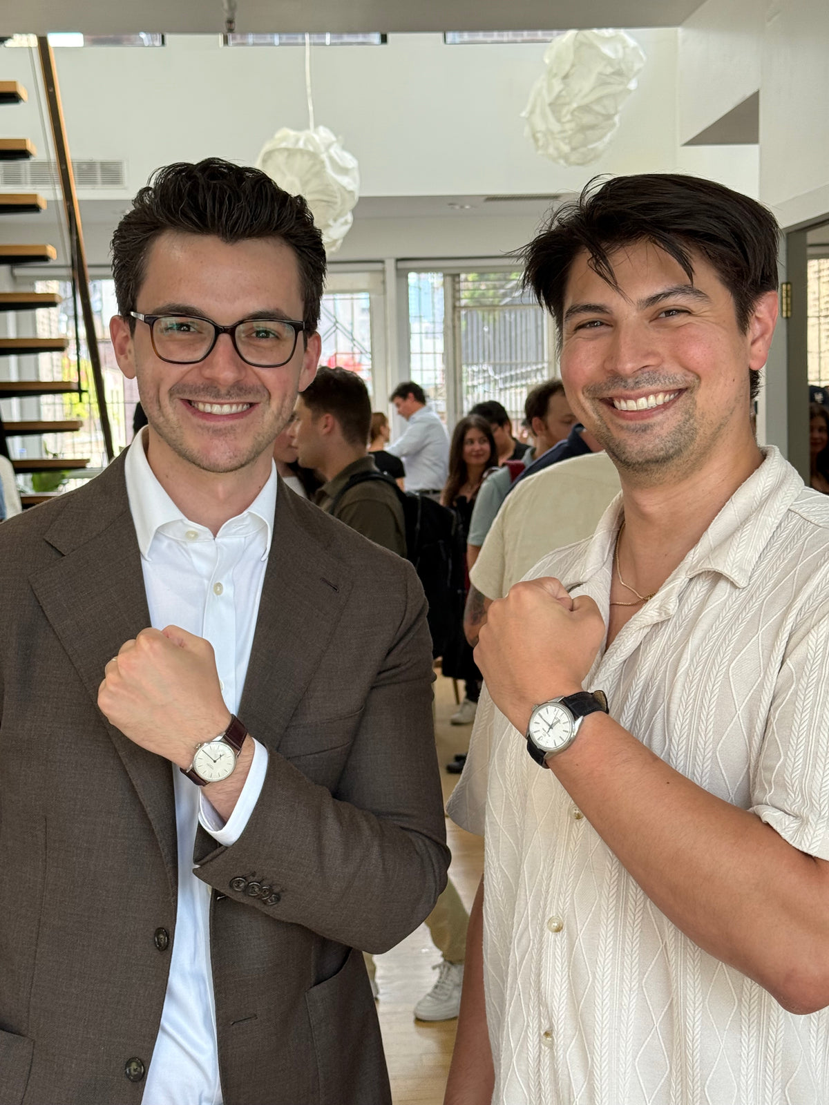 Two people at an event, each showing a watch on their wrist